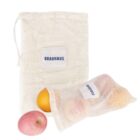 Two mesh produce bags with a BRAUHAUS label. One bag is partially filled with an orange and a pink fruit, possibly an apple. A separate apple is placed outside the bags. The bags are against a white background.