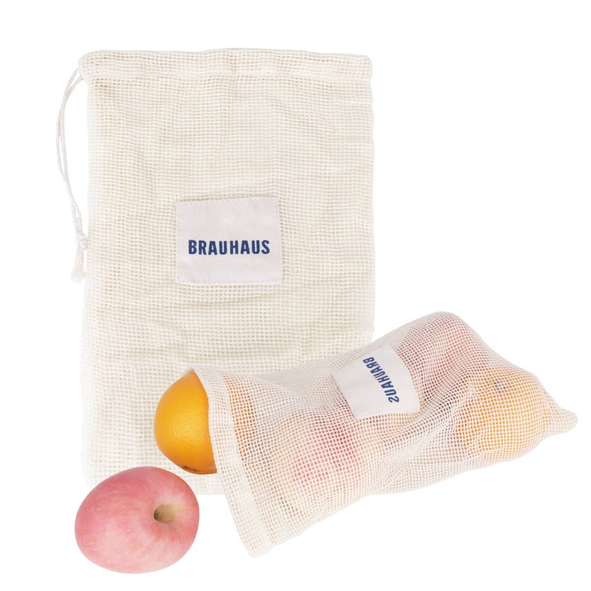 Two mesh produce bags with a BRAUHAUS label. One bag is partially filled with an orange and a pink fruit, possibly an apple. A separate apple is placed outside the bags. The bags are against a white background.
