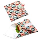 Reusable sandwich wraps with a colorful geometric leaf pattern in orange, red, and black. One wrap is open, showcasing a sandwich with lettuce and tomato inside. The other wrap is folded and closed, displaying a small logo tag.