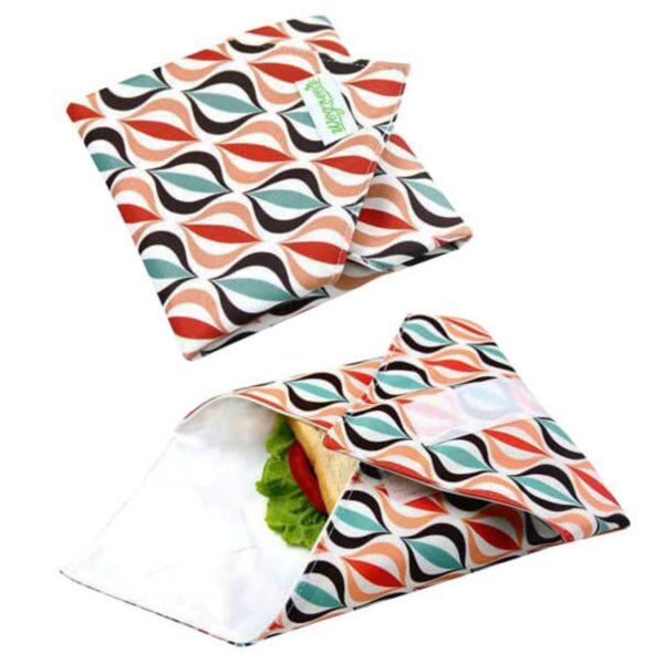 Reusable sandwich wraps with a retro leaf pattern in orange, red, and teal. One wrap is flat, while the other is opened, showing a sandwich inside.