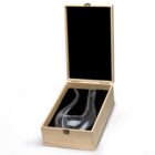 A glass wine decanter in a wooden box with a black velvet lining. The decanter has a curvy, modern design and is positioned inside the open box on a light background.