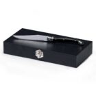 A sleek folding knife with a black handle rests on top of a closed black wooden box with a silver latch.