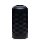 A sleek black cylindrical container with a textured, dimpled surface stands upright. It has a smooth, rounded opening at the top. The container is set against a white background.