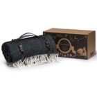 A rolled dark gray picnic blanket with white tassels and leather straps is placed next to a brown box with decorative illustrations and the text Arbrello Picnic Blanket.