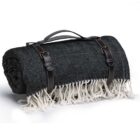 A rolled-up black herringbone-patterned blanket with white fringes, secured by brown leather straps and a handle.