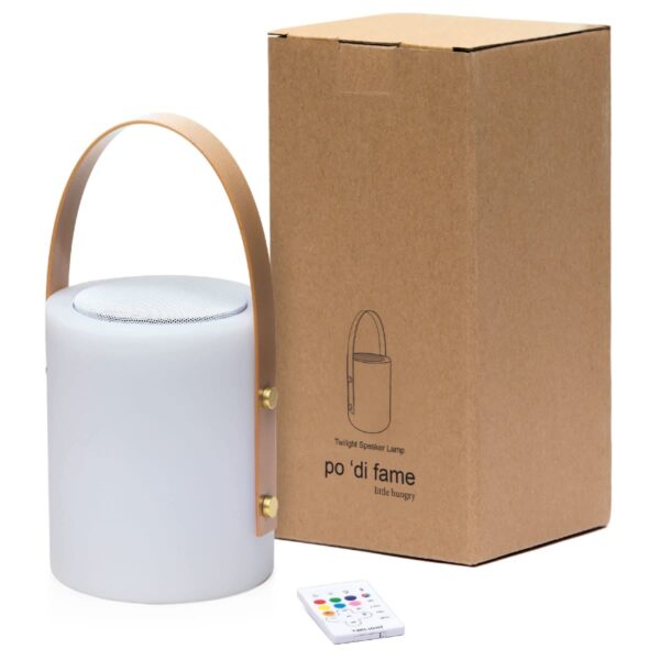 A portable speaker lamp with a leather handle, next to a cardboard box featuring its illustration. A small remote control is placed beside them. The box has po di fame little hungry printed on it.