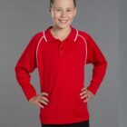 Smiling child in a red long-sleeve polo shirt with hands on hips against gray background.