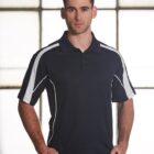 A man standing in front of a large window wearing a black polo shirt with white stripes on the shoulders. He has short brown hair and is looking directly at the camera with a neutral expression.