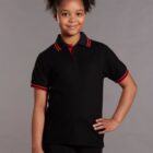 Smiling girl in a black polo shirt with red trim, standing against a gray background.