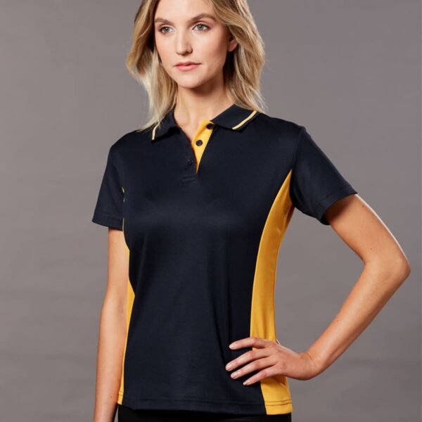 Person wearing a dark polo shirt with yellow side panels, standing against a gray background.