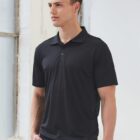 Man in black polo shirt standing near a window.