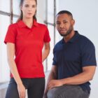 Two people in red and navy polo shirts sitting in a brightly lit room.