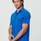 Man in a blue polo shirt standing against a neutral background.