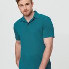 Man wearing a teal polo shirt stands against a light gray background.
