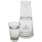 A clear glass carafe filled with water, labeled Campfire Industries, stands beside a matching glass tumbler also half-filled with water. Both objects are placed against a plain white background.