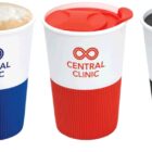 Three Central Clinic branded cups with different color lids and grips: blue, red, and black. The blue lid is detached. The cups feature a logo with two interlocking circles and text in the center.