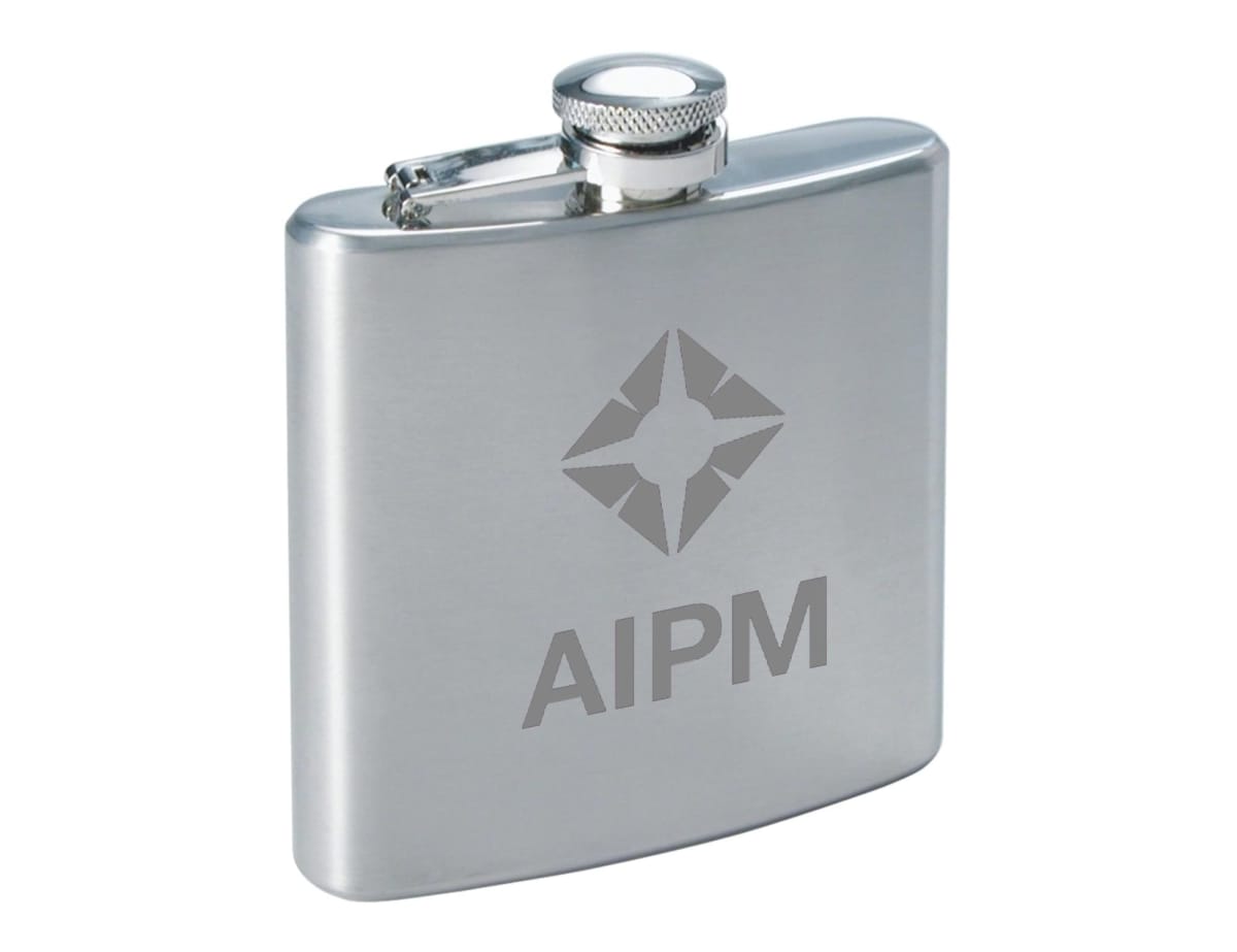 A stainless steel hip flask with a textured finish, featuring the engraved letters AIPM and a star-like logo design above it. The flask has a rounded bottom edge and a screw-on cap attached by a hinge.