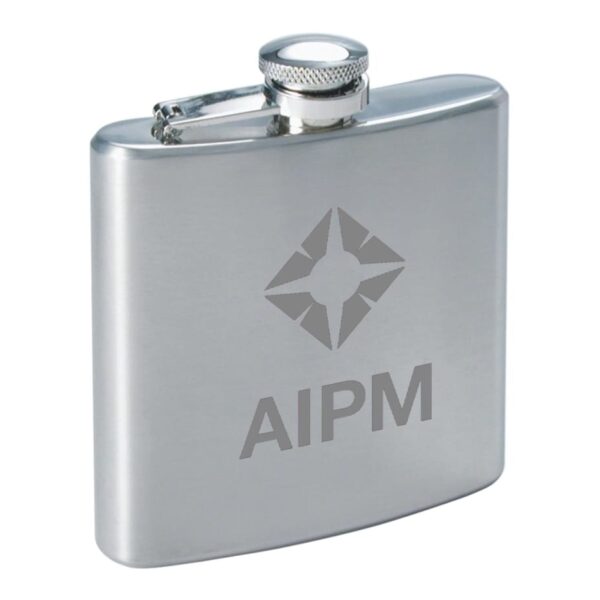 A silver hip flask with a screw cap. The front features a geometric logo and the letters AIPM engraved below. The flask has a sleek, reflective finish.