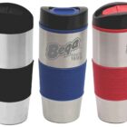 Three stainless steel travel mugs with rubber grips are shown. The grips are black, blue, and red. Each mug features a logo and the text Since 1899. The lids are black, with one red accent.