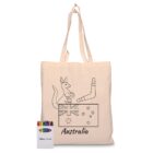 A cream tote bag with an outline drawing of a kangaroo, a boomerang, and the Australian flag. The word Australia is written below. A small pack of colored crayons is placed beside the bag.