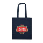 A navy blue tote bag with the Stella Artois logo in red and white on the front, featuring decorative gold detailing and the year 1366. The bag has two long handles.