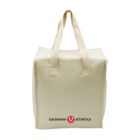 A beige canvas tote bag with two handles is shown. It features the Lululemon Athletica logo and name in black and red near the bottom. The bag has a boxy shape.