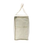 A beige fabric bag with a zipper on top and a side pocket. It has a single handle for carrying and is shown in a standing position, displaying its rectangular shape.