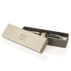 A silver and black pen is partially inside an open, elegant gray box on a white surface. The box has the word Parker printed on it, indicating the brand of the pen.