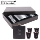 A gift set includes a black flask labeled House of Liquor, four black shot glasses, and two metallic shot cups. These are presented in an open black box with the text Modern Alchemist: Cocktails, Creativity, Mixology above it.