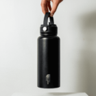 A hand holds a large black water bottle vertically by its handle against a plain white background. The bottle has The North Face logo near the bottom.