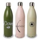 Three stainless steel water bottles are standing side by side. The bottles are green, pink, and beige, each with different logos resembling Dove, Hando, and Converse. They have screw-on lids and a sleek, modern design.