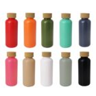 Ten colorful cylindrical bottles with cork lids are displayed in two rows. The top row includes red, orange, green, turquoise, and dark gray bottles. The bottom row has pink, beige, white, light gray, and black bottles.