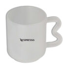 A transparent mug with a heart-shaped handle, displaying the Nespresso logo on one side. The mug has a sleek and modern design.