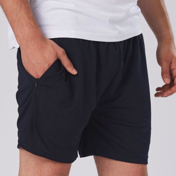 A person wearing a white t-shirt and black shorts stands with one hand in their pocket against a light gray background. The focus is on the shorts, which have a textured appearance.