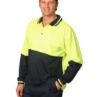 A person wearing a high-visibility, two-toned long-sleeve polo shirt in neon yellow and dark blue smiles with one hand in their pocket against a plain white background.