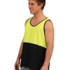 A person wearing a sleeveless tank top with a bright yellow upper half and black lower half stands with a slight smile and looks to the side. They are also wearing light blue jeans against a plain white background.