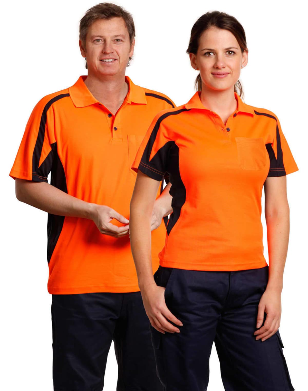 Two people wearing bright orange and black polo shirts stand side by side. The person on the left is smiling and has short hair, while the person on the right has long hair tied back. Both are wearing dark pants.