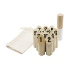 Wooden number game pieces arranged in a cluster, each marked with a black number. A white and beige cylindrical object stands beside them. A beige drawstring bag is lying flat on the left.