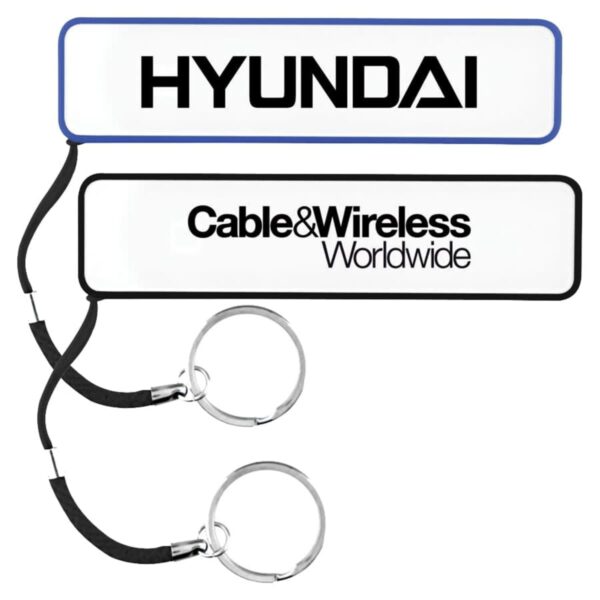 Two white keychains are shown. The top one reads HYUNDAI in black text with a blue border. The bottom one reads Cable&Wireless Worldwide in black text with a black border. Both have black straps and metal key rings attached.