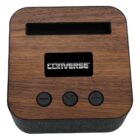 A square speaker with a wood-like top and black fabric sides, featuring the Converse logo on the front. It has three buttons: play/pause, previous, and volume up.