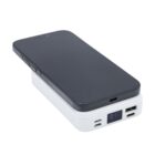 Black smartphone charging wirelessly on a white power bank with digital display.