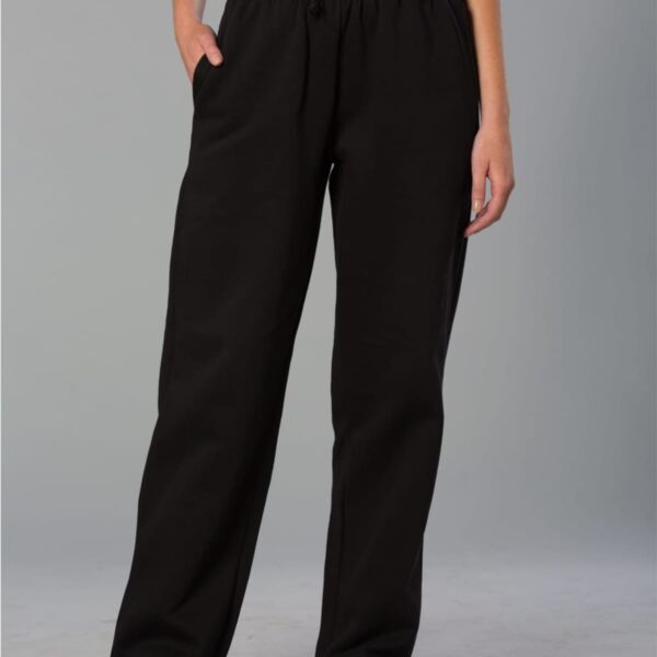 A person is wearing black, loose-fitting sweatpants with hands in pockets. The pants have an elastic waistband with a drawstring. They are paired with a gray top and black sneakers, standing against a plain gray background.