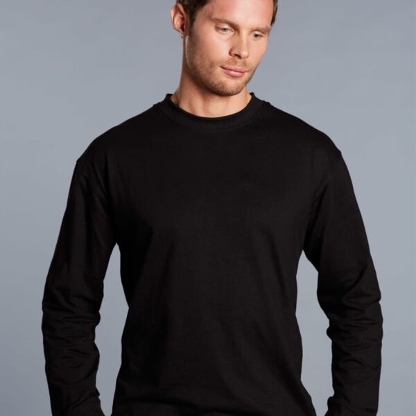 A man with short hair wearing a black long-sleeve shirt stands against a plain gray background, looking down with a neutral expression.