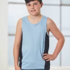A young boy wearing a light blue sleeveless shirt with black side panels stands indoors. He has short brown hair and is posing with one hand on his hip. The background features blurred glass windows.