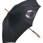 A black umbrella with a wooden handle, featuring the logo of The Body Shop in white on one panel. The umbrella is open and positioned at an angle.