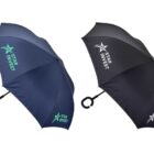 Two umbrellas are displayed against a white background. One is dark blue, and the other is black. Both have Star Invest logo printed in white and green on their canopies. They feature a C-shaped handle.