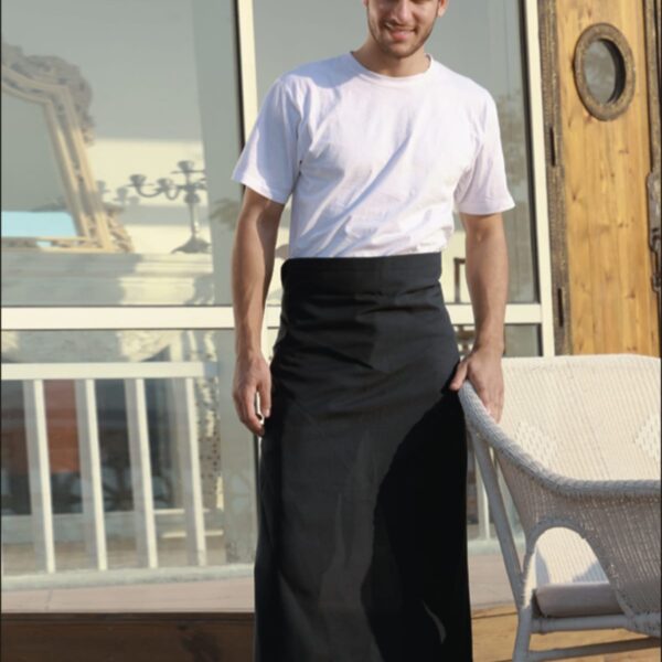 A person wearing a white shirt and black apron stands on a wooden deck, next to a wicker chair. The person is smiling and looking at the camera. The text BOCINI and HOSPITALITY is displayed on the image.