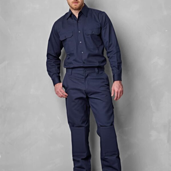 A man wearing a navy blue work uniform stands against a gray background. The uniform consists of a button-up shirt and matching pants. He is also wearing tan work boots.