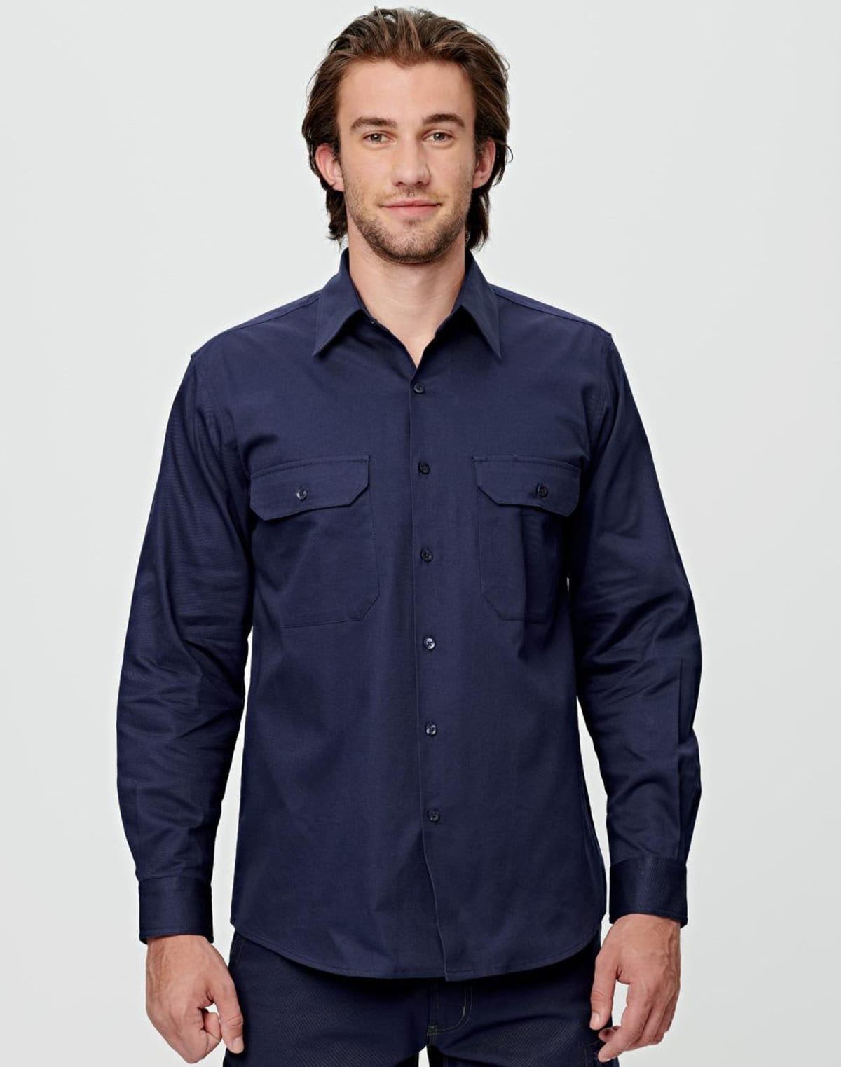A person with long hair is wearing a long-sleeved, dark blue button-up shirt with two chest pockets, standing against a plain background.