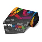 A rolled-up necktie with a black base, featuring colorful geometric patterns and the words NETACUBE printed multiple times in gray and various colors. The design includes shades of red, orange, yellow, green, blue, and purple.